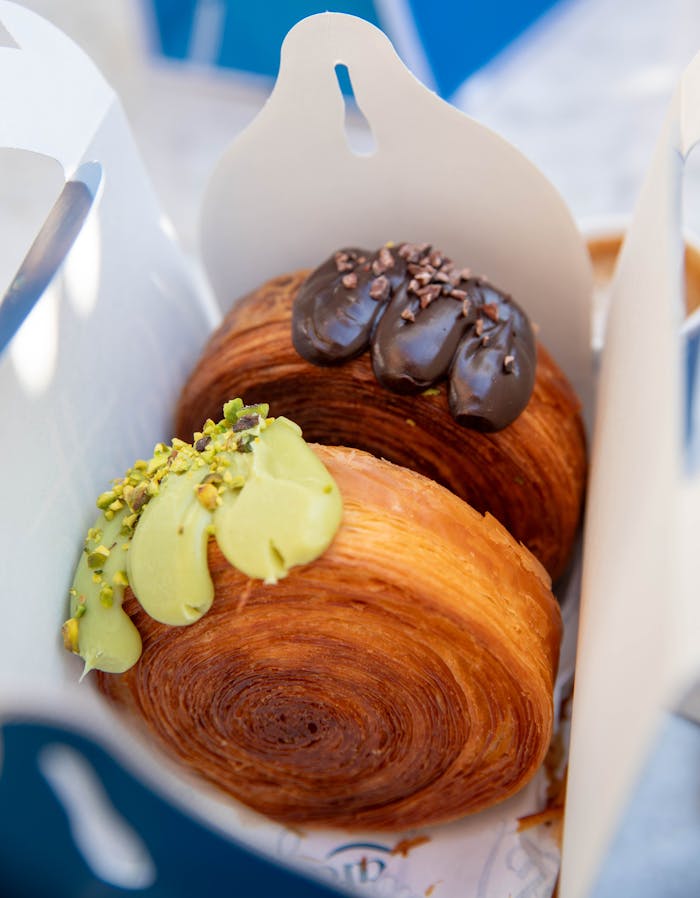 Delicious pastries topped with pistachio cream and chocolate, photographed in a New York bakery.
